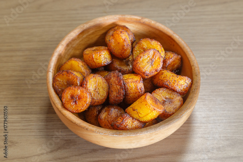 Aloco, accompagnement de bananes frites dans un bol sur une table en bois