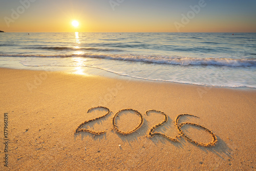2026 text symbol of new year on the sea sand beach shore during sunset.
