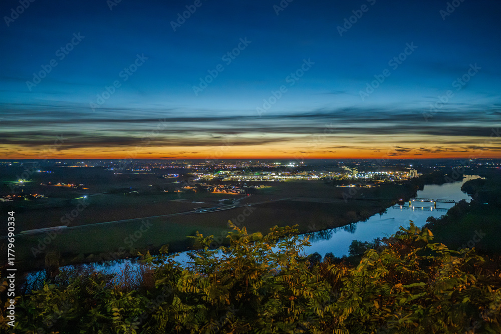 Fototapeta premium Sonnenuntergang über der Stadt mit Fluss und ländlicher Umgebung am Abend