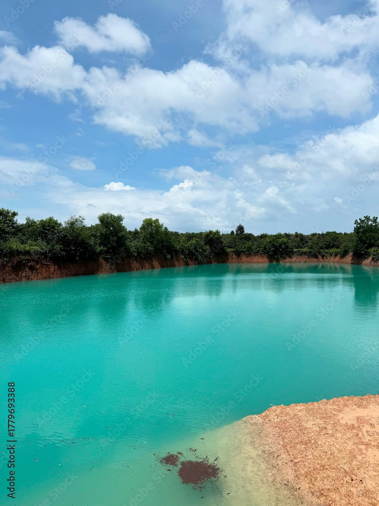 Obraz premium Clear turquoise water reflects clouds and trees.