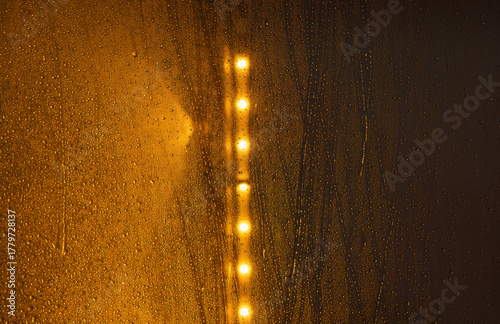 Spray and water drops on orange lit background in a carwash making interesting pattern