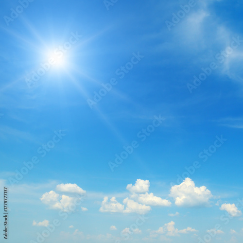 Fotografija Bright Sunburst in Clear Blue Sky with Few White Clouds