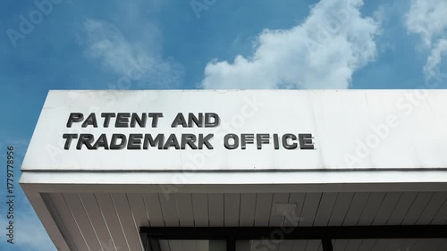 A Patent and Trademark Office word sign displayed on a governmental building under a clear blue sky, symbolizing intellectual property, innovation, legal registration, and protection