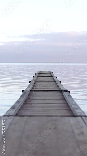 Old wooden pier at the sea, Calm waters and cloudy sky create an peaceful view.
