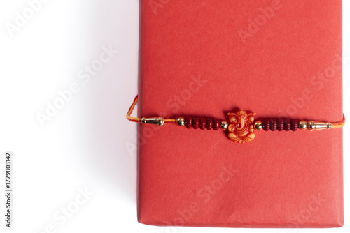Red gift box wrapped in a soft bracelet for the celebration of the Raksha Bandhan festival.