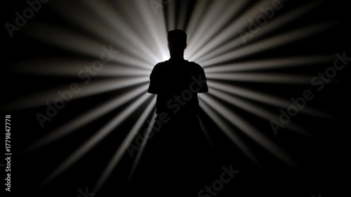 A dark figure of a martial arts master practices his skills, performing various stances in front of a powerful white light, creating radial rays of illumination.