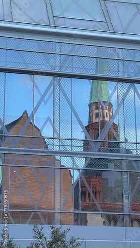 Reflection of the historic Frankfurt Cathedral in the glass facade of a modern building. Contrast of old Gothic architecture and contemporary urban design in the city center