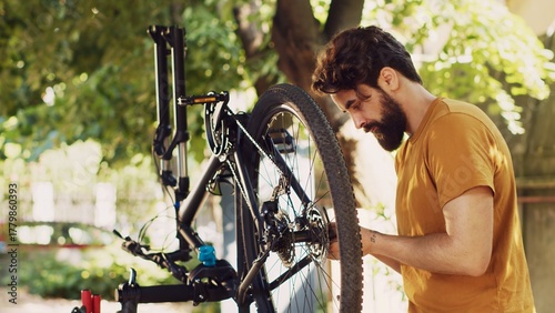 Obraz na płótnie Sports-loving man engrossed in fixing modern bicycle with professional equipment