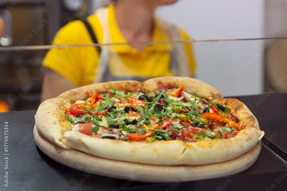 Obraz premium Pizza in the pizzeria window and cook