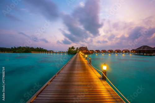 Fototapeta Naklejka Na Ścianę i Meble -  Tranquil closeup calm sea water waves with palm trees. Beautiful blue hours with bungalows. Tropical island beach landscape exotic shore coast. Summer vacation, holiday amazing nature, Maldives.