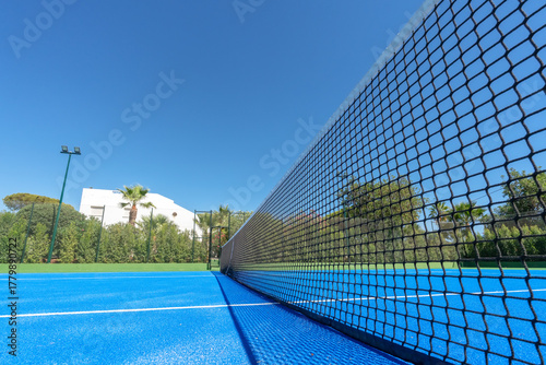 Sunny tennis arena, Open court under bright sky, Vivid outdoor tennis facility with clear weather, Brightly lit tennis court with vivid surroundings and seating
