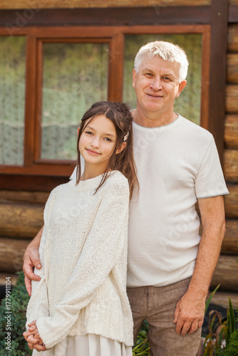 Family portrait - Gray-haired grandfather hugs his granddaughter