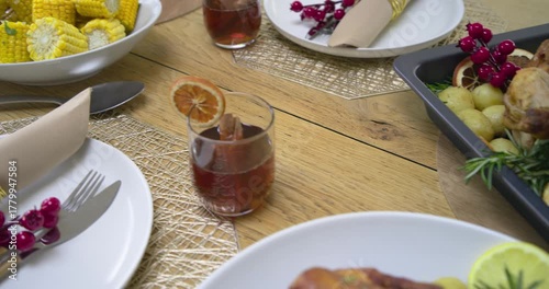 Camera panning across table from corn bowl to garnished drink, pan, plating chicken for serving