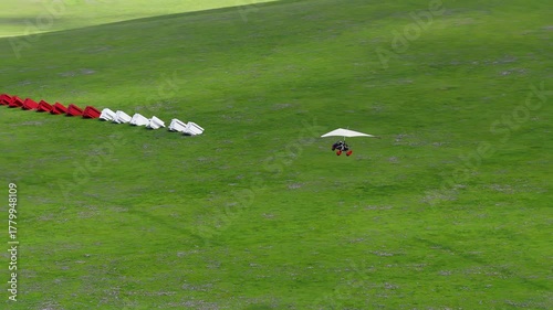 A powered hang glider flying over the grasslands