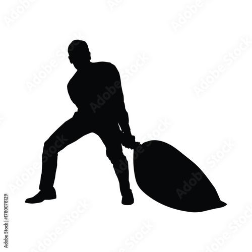 Silhouette of Man Straining to Drag a Large, Heavy Sack or Bag, Showing Manual Labor.
