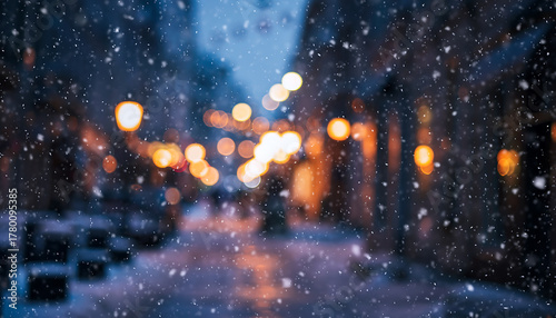 Fototapeta Naklejka Na Ścianę i Meble -  Softly falling snow illuminates a blurry city street at dusk