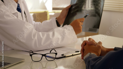 A doctor reviews a chest X-ray with a patient during a medical consultation, explaining diagnosis and treatment options in a professional healthcare setting.