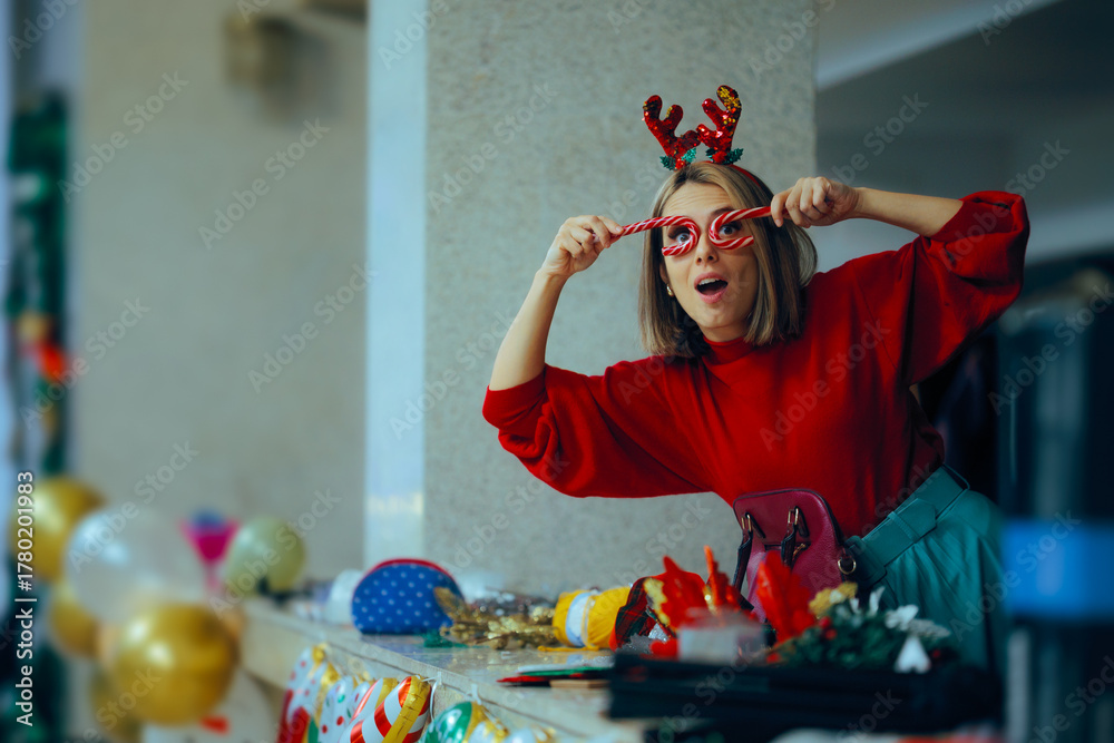 Fototapeta premium Christmas Party Decorator Holding Candy Canes in front of her Eyes. Cheerful event organizer feeling excited about the Xmas festivity 