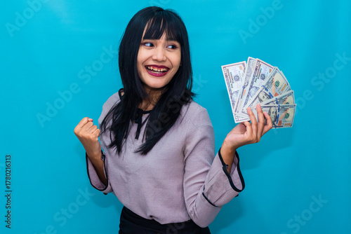 Laughing joyfully, the woman lifts her cash with confidence and happiness. Ideal for rewards, business success, and positive lifestyle campaigns.