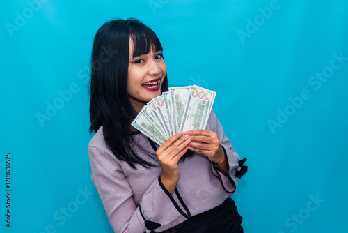 A happy woman peeks playfully over her money, smiling confidently. Ideal for wealth, success, and reward-based marketing.