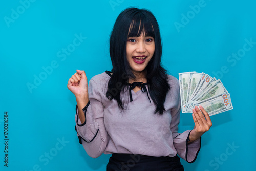 A cheerful woman raises her fist while smiling brightly and holding cash. Ideal for bonus, motivation, and income-related campaigns.