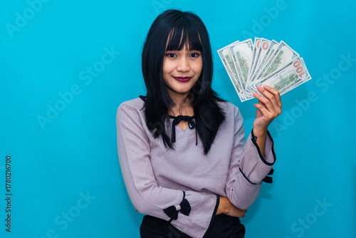 The woman smiles and points to her cash, expressing excitement and pride. Ideal for e-commerce, rewards, and financial success visuals.
