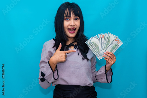 Smiling broadly, the woman proudly displays her dollar bills with an energetic pose. Ideal for business success, investment, and reward-themed marketing.