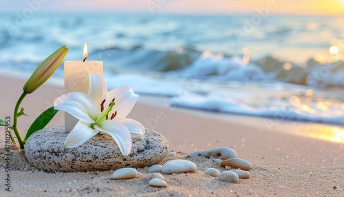 Burning candle with white lily flower near a stone podium on sea sand beach with wave background.