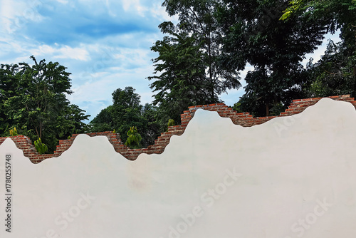 Decorative curved fence wall. Beautiful stuccoed brick wall features unique and attractive design, characterized by uneven, varying height levels. rendered brick wall design non uniform wall heights.