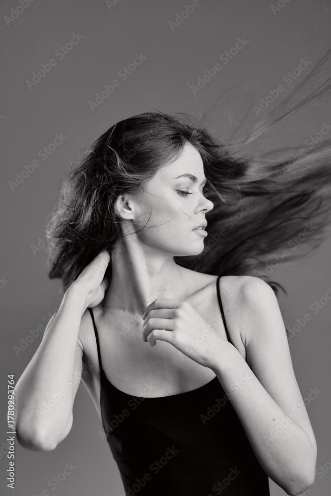 Naklejka premium Black and white portrait of a young woman with flowing hair wearing a sleeveless top in calm expression