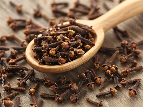 Wallpaper Mural Aromatic cloves spilling from wooden spoon, inviting warmth and spice for culinary creations, holiday baking, and cozy autumn recipes, a taste of tradition Torontodigital.ca