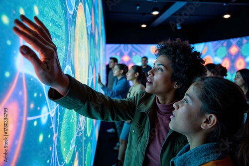 Group of engaged visitors interacting with a large, glowing interactive digital screen at a modern museum exhibit