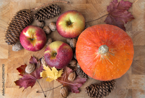 top view on bright red apples  and orange pumpkin,  walnuts and pine cones wi...
