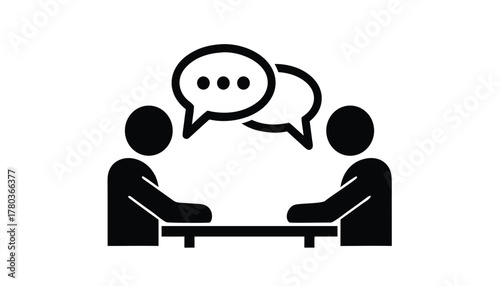 Two people sitting at a table with speech bubbles above their heads, representing conversation or discussion