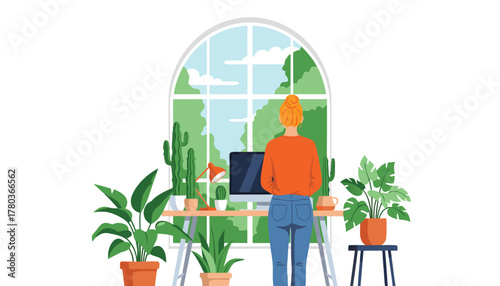 Woman standing at a desk with a computer in front of a large arched window overlooking a lush green garden, surrounded by houseplants