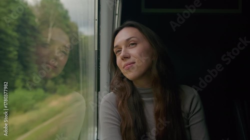 Young woman enjoys a scenic train journey through lush green landscapes