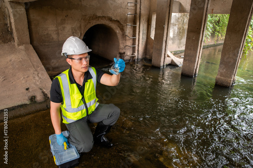 Environmental Scientist Collecting Water Samples Under Bridge for testing