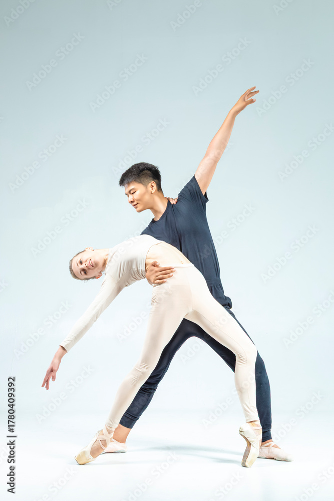 Obraz premium Dance Concepts. Loving Couple of Asian Man and Caucasian Woman Performing As Ballet Dancers Over Grey in Studio As Classical Choreography and Ballet Dancing.