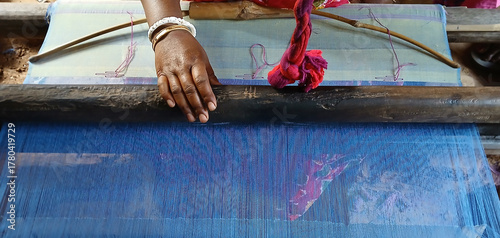 Handloom weaver working on loom.