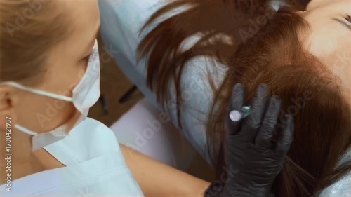 Cosmetologist performing PRP injection for hair growth stimulation. Aesthetic specialist administering plasma therapy into scalp to rejuvenate follicles. Skin care professional using syringe to apply