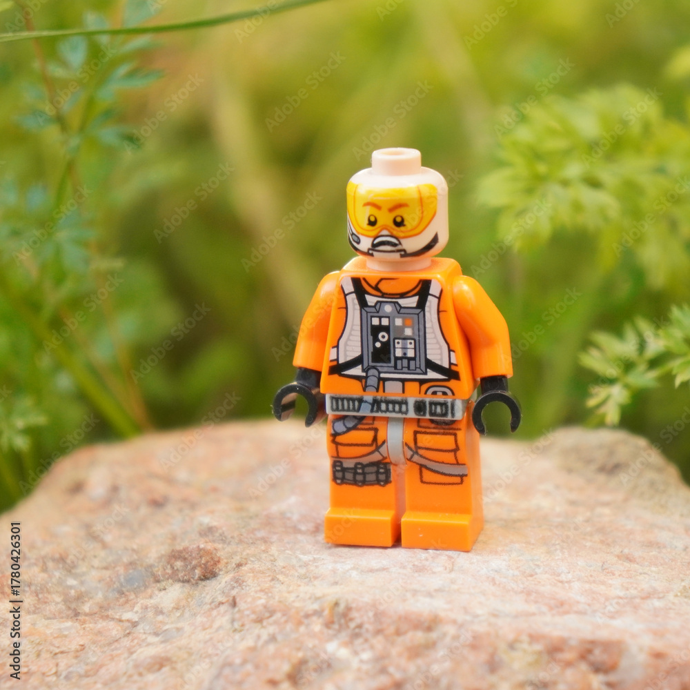 Naklejka premium Lego Star Wars X-Wing pilot minifigure standing on a rock with a green background