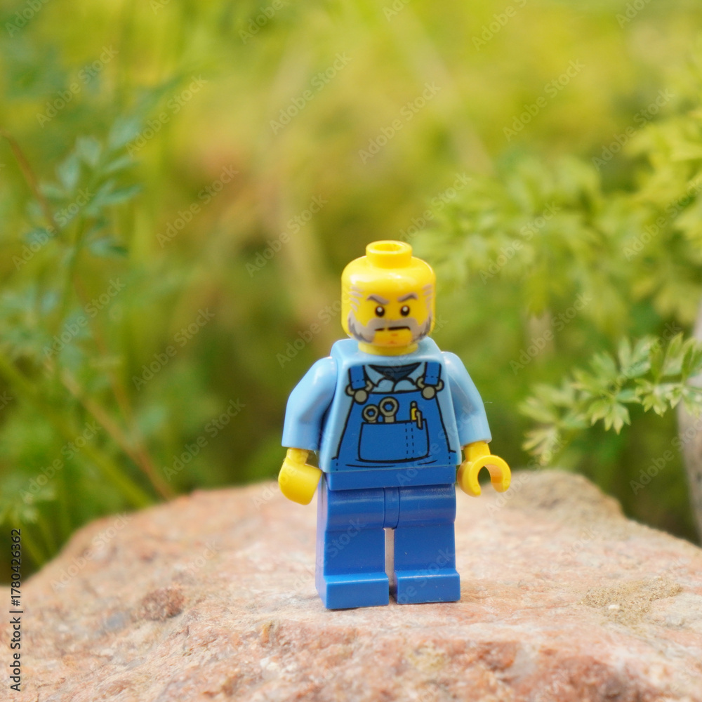 Naklejka premium Lego minifigure of a mechanic standing on a rock with a green background