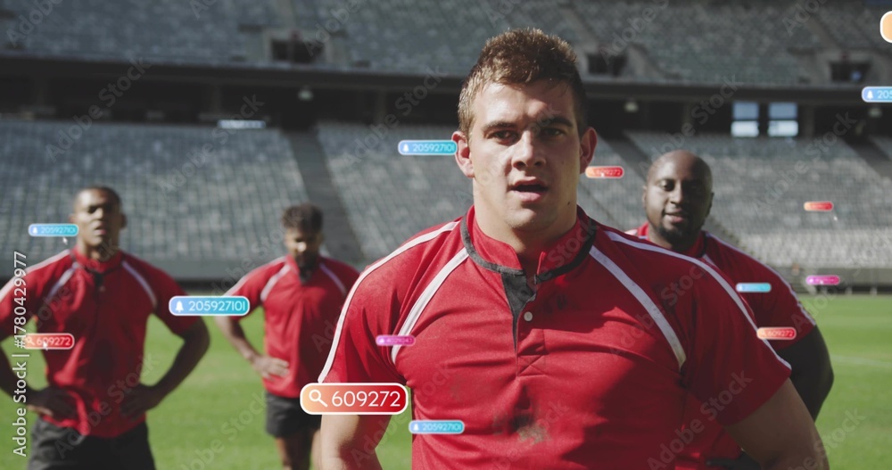 Fototapeta premium Standing front-center athlete wearing red jersey and black shorts on grass pitch, with digital tags