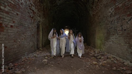 Group of girls in white robes in an old brick tunnel. Concept of mystical medieval life.