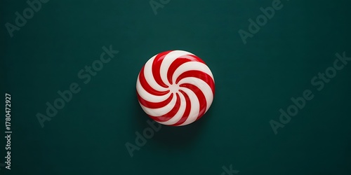 A single red and white striped peppermint candy is centered on a dark green background.
