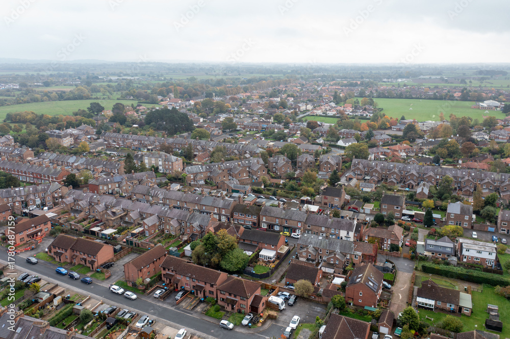 Naklejka premium Aerial drone photo of the market town of Thirsk in North Yorkshire, England showing rows of victorian terrace houses and homes on a gloomy dark bad weather rainy day in the winter time