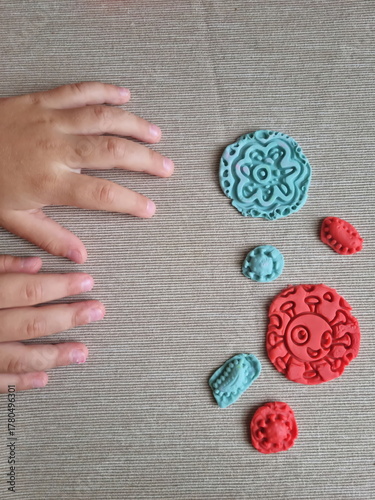 Covid and other respiratory virus molecules made of plasticine. Little toddler education moment in a playful mode. Bacteria made of playdough and kids' hands over the table. 