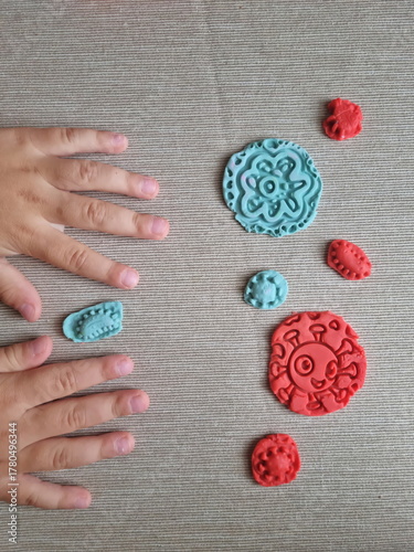 Covid and other respiratory virus molecules made of plasticine. Little toddler education moment in a playful mode. Bacteria made of playdough and kids' hands over the table. 