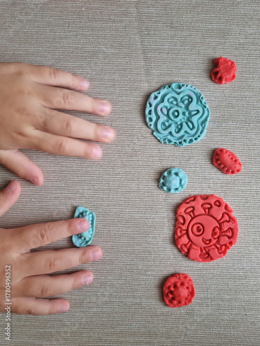 Covid and other respiratory virus molecules made of plasticine. Little toddler education moment in a playful mode. Bacteria made of playdough and kids' hands over the table. 