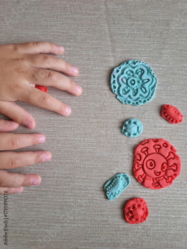 Covid and other respiratory virus molecules made of plasticine. Little toddler education moment in a playful mode. Bacteria made of playdough and kids' hands over the table. 